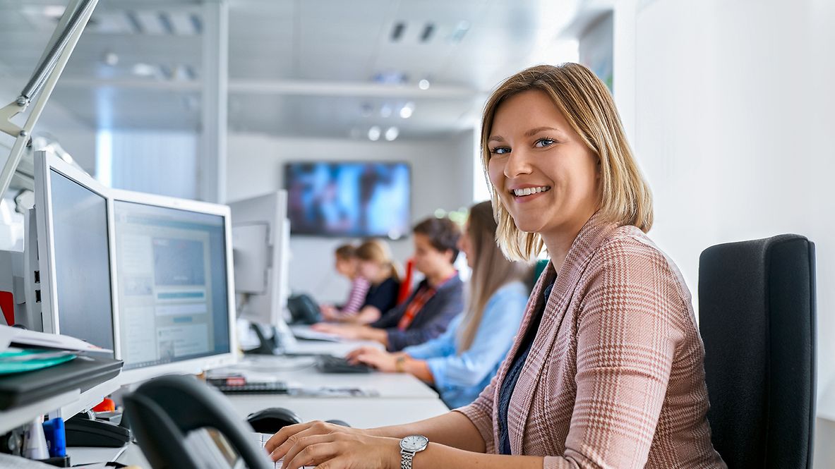 Eine Dualstudierende Dienstleistungsmanagement sitzt in einem Büro vor einem PC