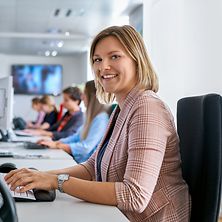 Eine Dualstudierende Dienstleistungsmanagement sitzt in einem Büro vor einem PC